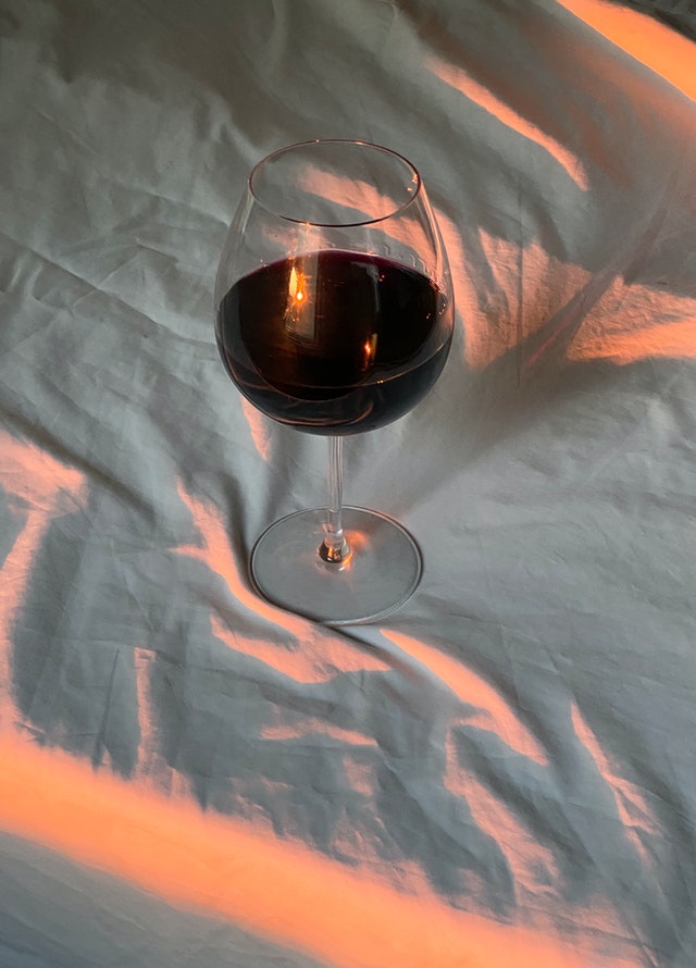 Красное вино в бокале на белой простыне