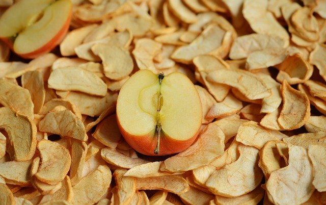 Свежая половинка яблока лежит на подсушенных дольках